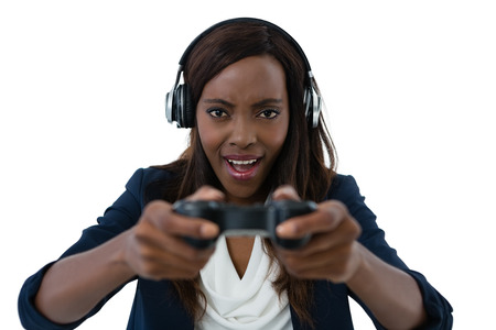 Young businesswoman wearing headphones while playing video game against white background