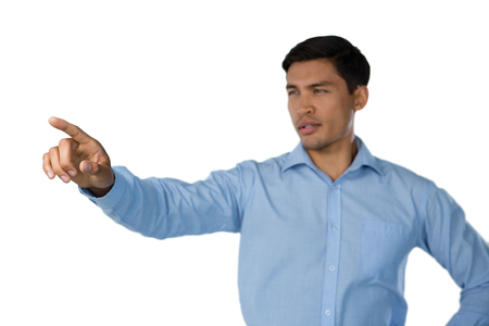 Young businessman touching invisible screen standing against white backgroundの写真素材