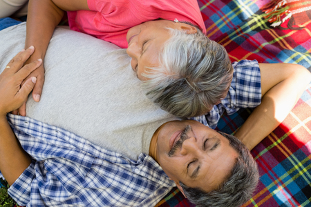 Senior couple laying on blanket at the parkの写真素材