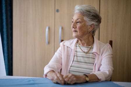 Thoughtful senior woman sitting at table in nursing home