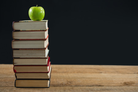 Green apple on book stack against black backgroundの写真素材