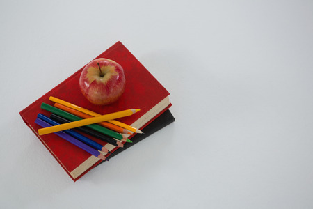 Overhead view of apple and color pencil on book on white backgroundの写真素材