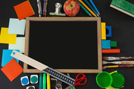 Overhead view of blank slate with various school supplies on black backgroundの写真素材