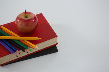 Apple and color pencil on book on white backgroundの写真素材
