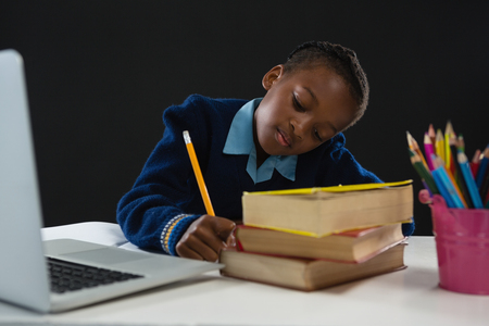 Schoolgirl doing homework against black backgroundの写真素材