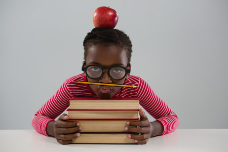 Portrait of schoolgirl leaning on books stack against white backgroundの写真素材