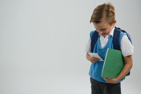 Schoolboy using mobile phone against white backgroundの写真素材