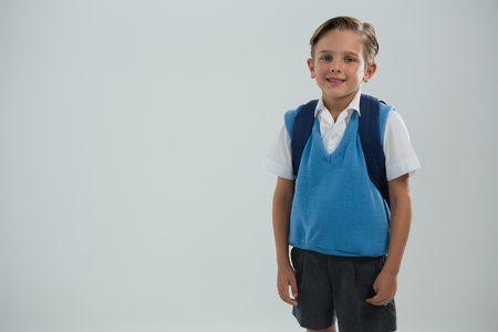 Portrait of cute schoolboy standing against white backgroundの写真素材