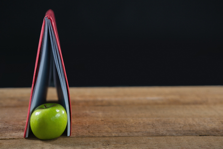 Close-up of apple and book on wooden tableの写真素材
