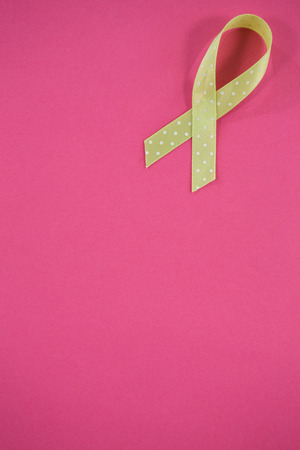 High angle view of spotted green Lymphoma Awareness ribbon on pink backgroundの写真素材