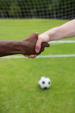Close up of soccer player doing handshake while standing on playing fieldの写真素材