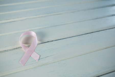 High angle view of pink Breast Cancer Awareness ribbon on white wooden tableの写真素材