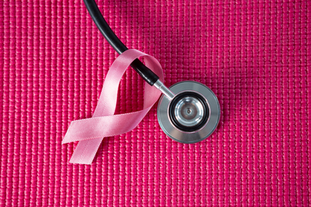 Directly above view of stethoscope by pink Breast Cancer Awareness ribbon on fabricの写真素材