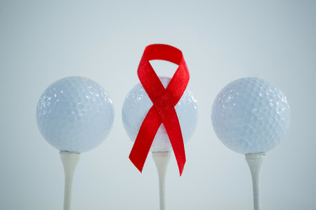Close-up of red AIDS Awareness ribbon on golf ball against white backgroundの写真素材