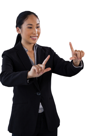 Smiling businesswoman with finger frame gesture while standing against white backgroundの写真素材