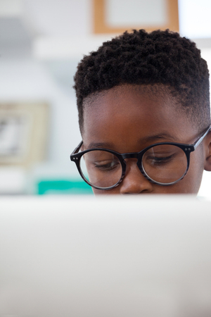 Close up of kid businessman wearing eyeglasses using computer while working in officeの写真素材