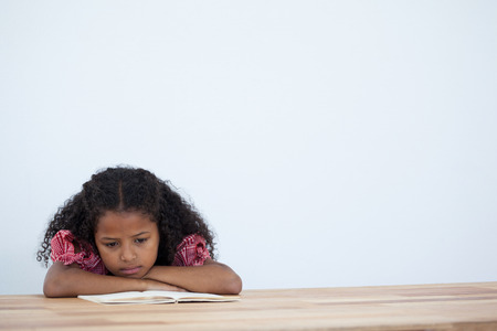 kid Businesswoman reading book while leaning on desk against white backgroundの写真素材