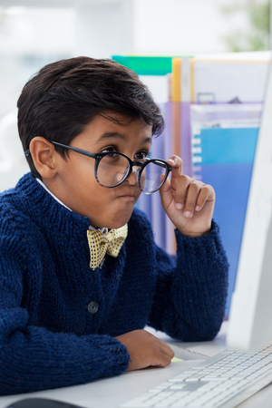 Businessman making face while looking at computer monitor while working at desk in officeの写真素材