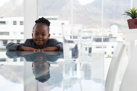 Portrait of smiling businesswoman with reflection leaning on conference table in officeの写真素材