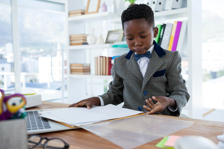 Businessman checking file while sitting at desk in officeの写真素材