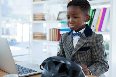 Sad businessman making face while looking at laptop in officeの写真素材