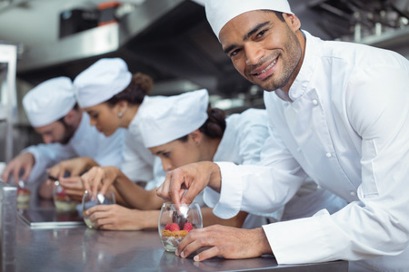 Smiling chefs finishing dessert in glass at restaurantの写真素材