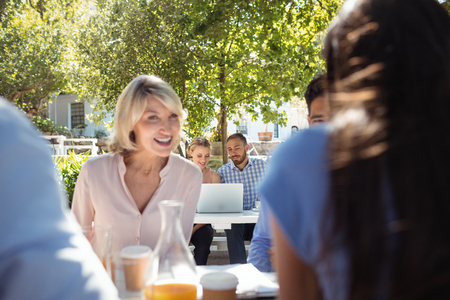 Smiling friends interacting with each other in restaurantの写真素材