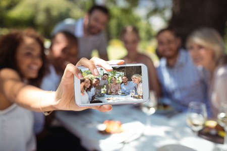 Friends taking selfie on mobile phone while having meal in restaurantの写真素材