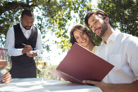 Friends placing order to waiter in restaurantの写真素材