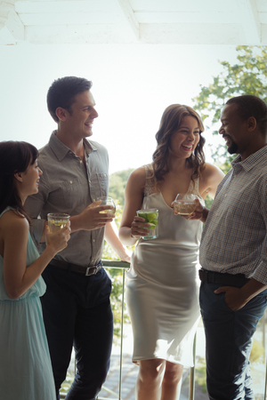 Group of friends interacting with each other while having cocktail drink in restaurantの写真素材