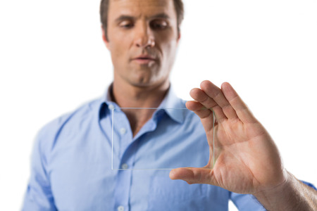 Male executive using glass mobile phone against white backgroundの写真素材