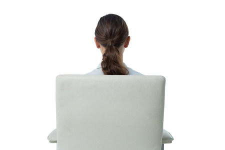 Rear view of female executive relaxing on chair against white backgroundの写真素材