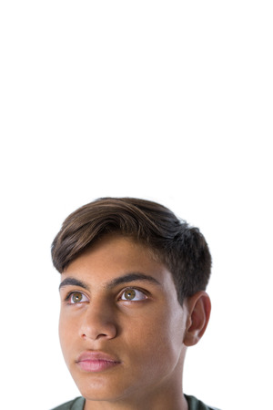 Thoughtful teenage boy looking away against white backgroundの写真素材