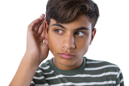 Teenage boy listening secretly with hands behind her ears against white background