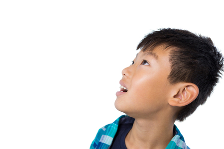 Thoughtful boy standing against white backgroundの写真素材