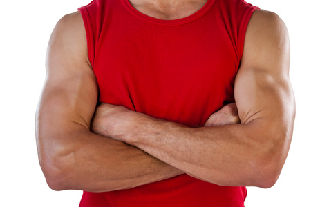 Midsection of sports player with arms crossed standing against white backgroundの写真素材