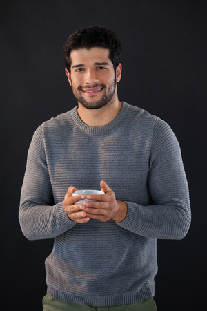 Portrait of smiling man holing a cup of tea against white backgroundの写真素材