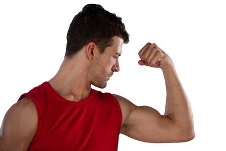 Close up of male athlete flexing muscles while standing against white background