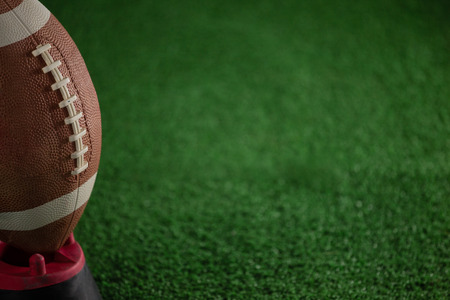 Cropped image of American football on tee at playing fieldの写真素材