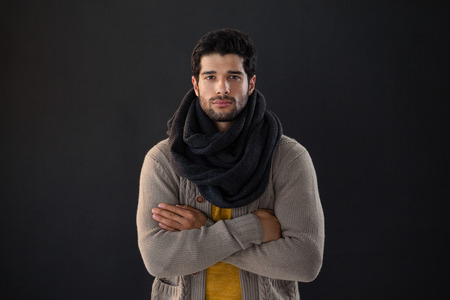 Portrait of man standing with arms crossed against black backgroundの写真素材