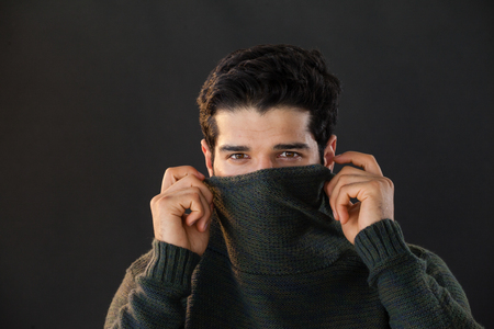 Portrait of man hiding face from scarf against white backgroundの写真素材