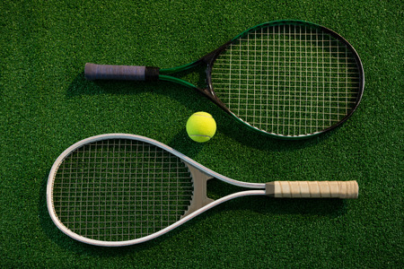 Overhead view of rackets with tennis ball on playing fieldの写真素材