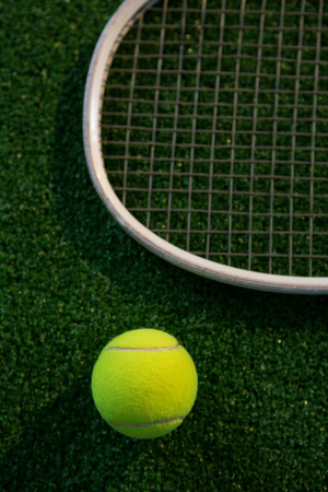Cropped image of racket by tennis ball on playing field