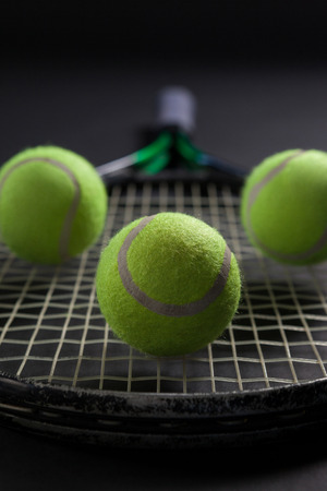 Close up of balls on tennis racket against black backgroundの写真素材
