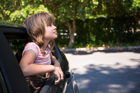 Thoughtful teenage girl looking through car windowの写真素材