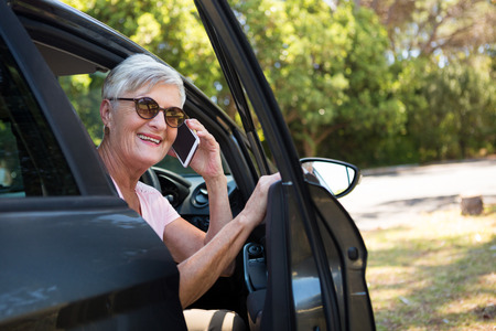 Active senior woman talking on mobile phone in car