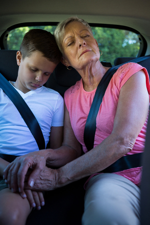Grandmother and grandson relaxing together in the back seat of car