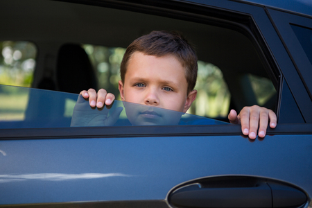 Portrait of teenage boy looking from open car windowの写真素材