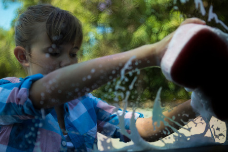 Teenage girl washing a car on a sunny dayの写真素材