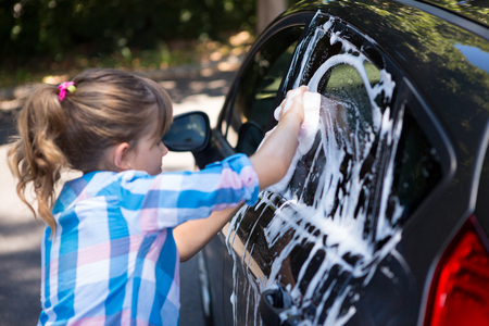 Teenage girl washing a car on a sunny dayの写真素材
